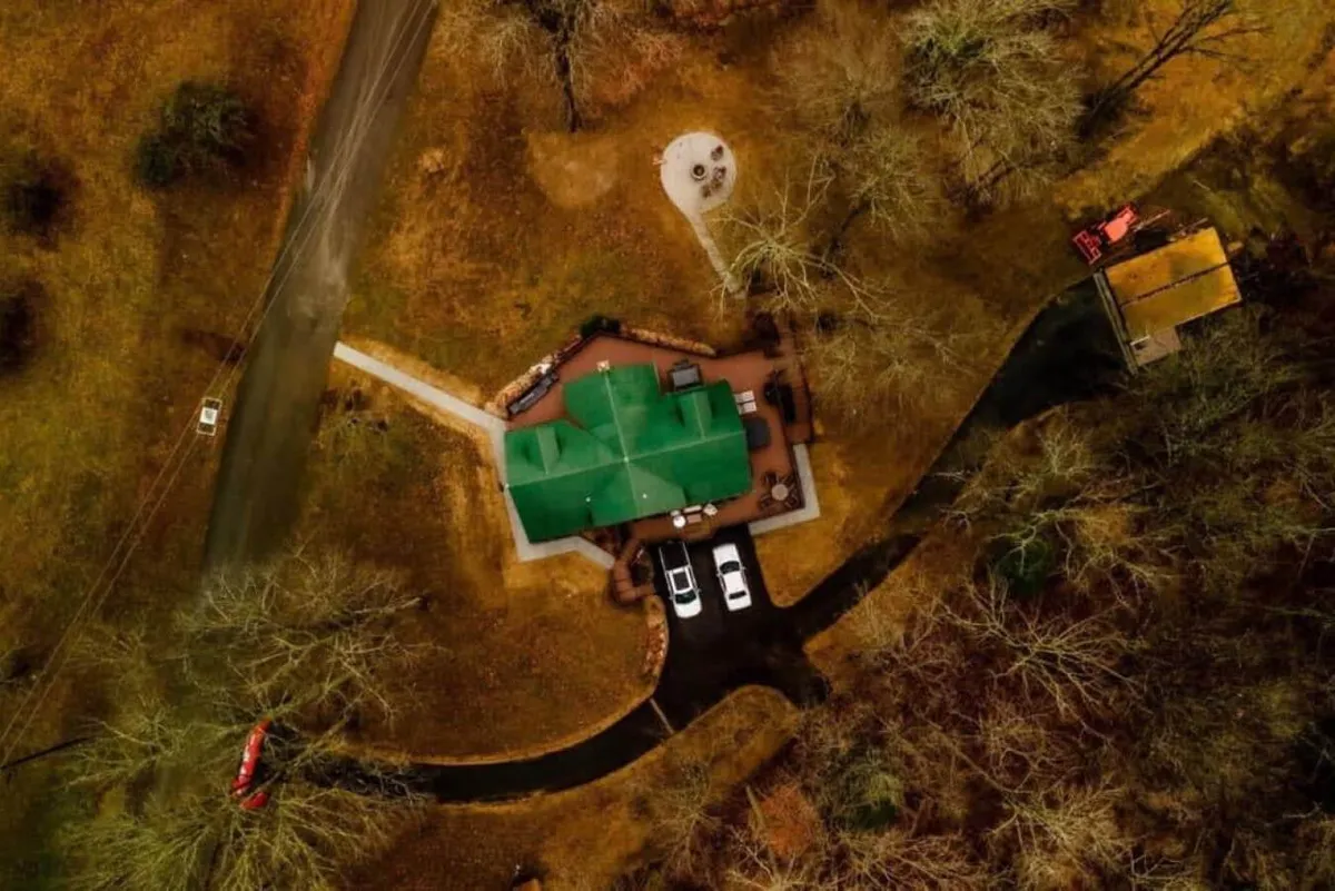 An exterior perspective featuring the home’s signature green roof, a circular patio surrounded by trees, and inviting outdoor spaces ideal for barbecues or nature-inspired gatherings.